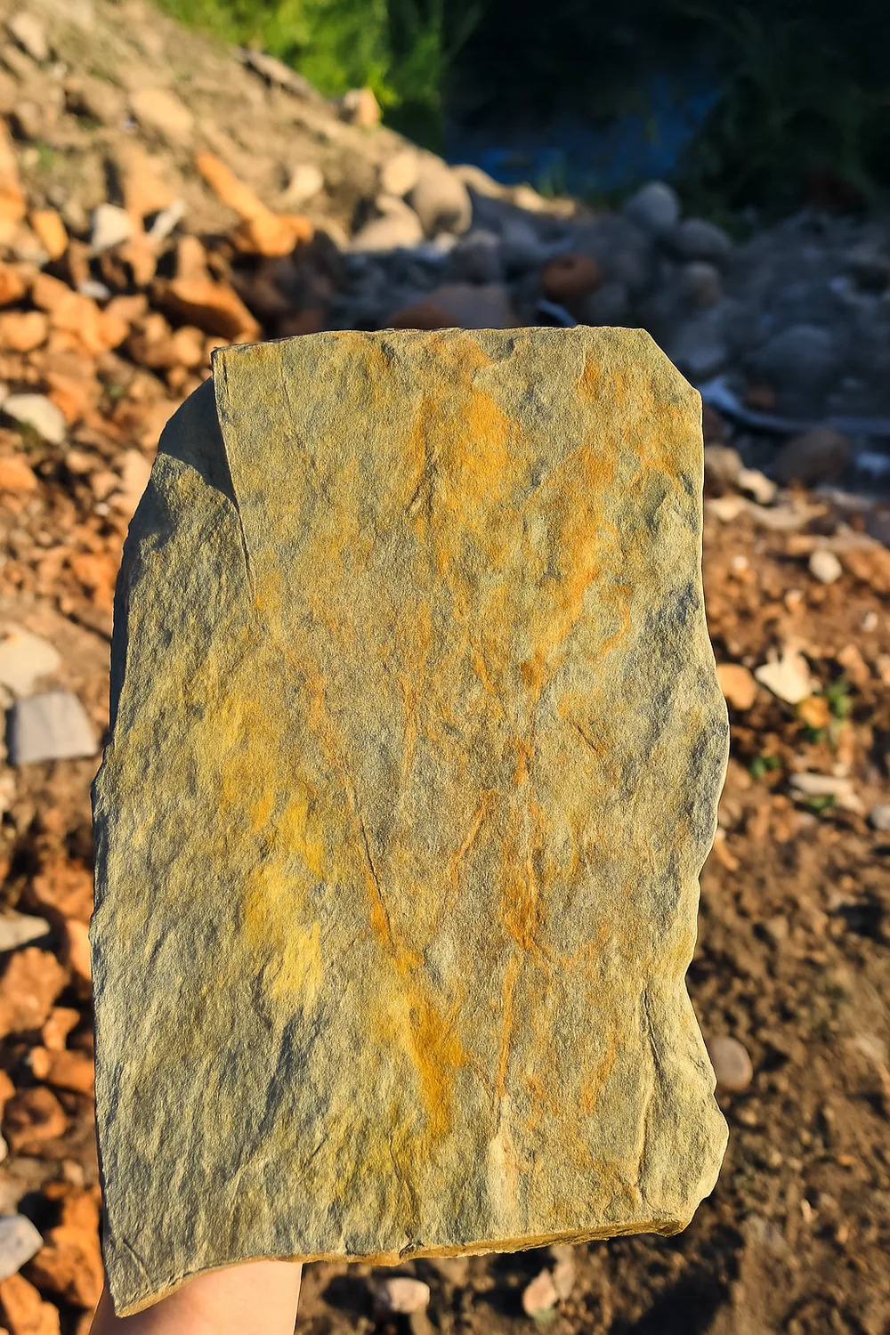 Piedra laja con tonos ocres sostenida en mano